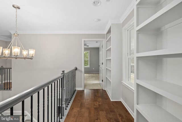 hall featuring dark hardwood / wood-style flooring, a chandelier, built in shelves, and ornamental molding