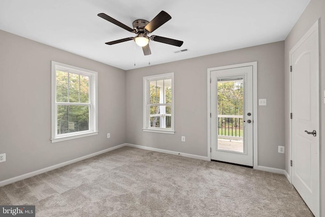 carpeted spare room featuring ceiling fan and plenty of natural light