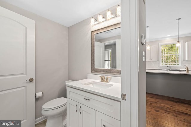 bathroom featuring hardwood / wood-style floors, ornamental molding, toilet, backsplash, and vanity