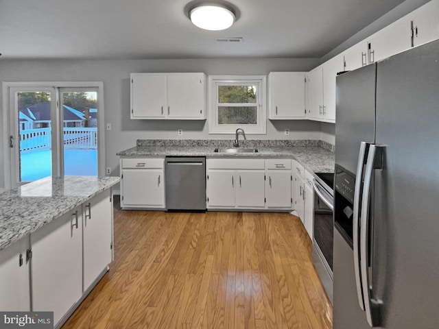 kitchen with appliances with stainless steel finishes, light hardwood / wood-style flooring, white cabinetry, and sink