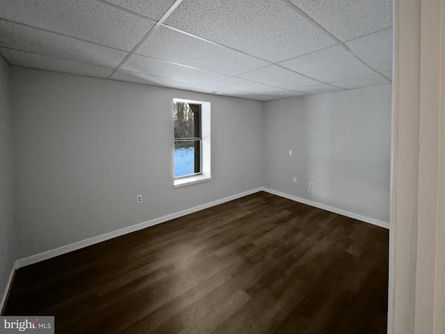 empty room featuring dark wood-type flooring and a drop ceiling