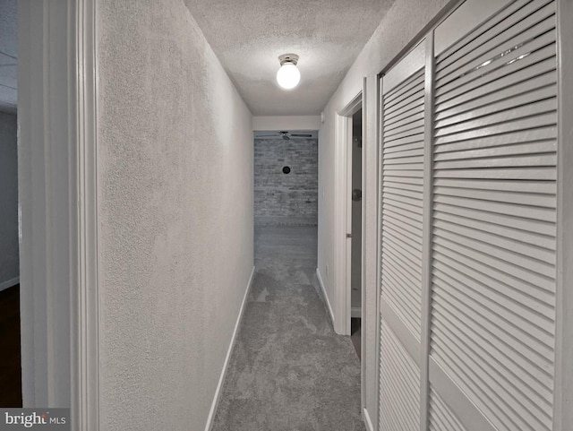 corridor featuring a textured ceiling and carpet floors