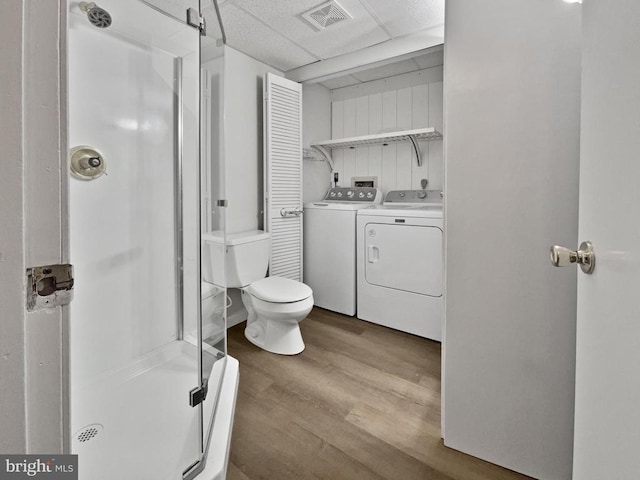 bathroom featuring independent washer and dryer, hardwood / wood-style floors, toilet, a paneled ceiling, and a shower with door