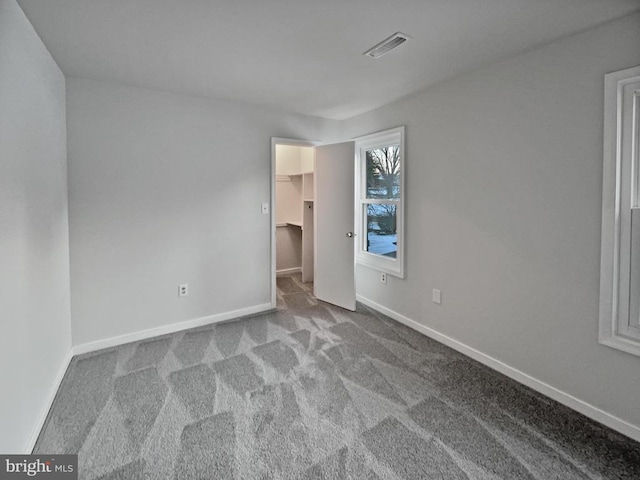 unfurnished bedroom with a closet, light carpet, and a spacious closet