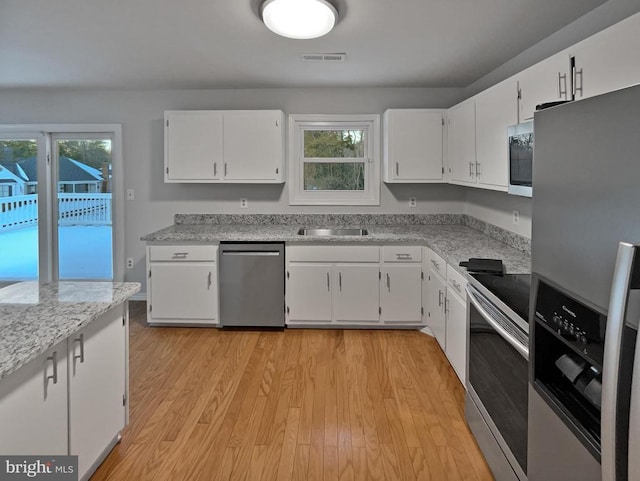 kitchen featuring stainless steel appliances, white cabinetry, sink, and light hardwood / wood-style flooring