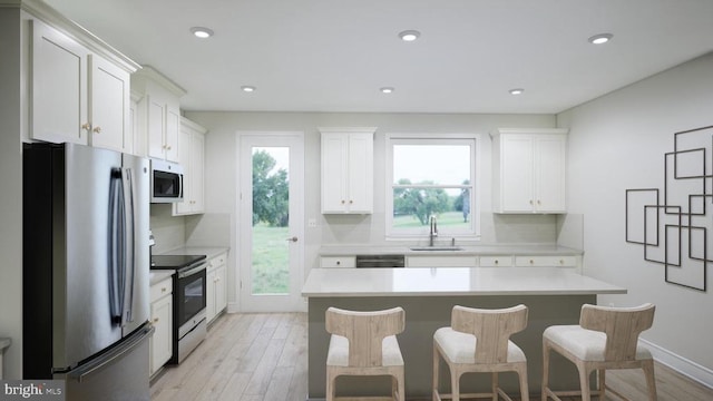 kitchen featuring stainless steel appliances, a kitchen bar, a kitchen island, white cabinetry, and sink