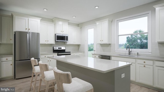 kitchen with sink, white cabinetry, a center island, light hardwood / wood-style flooring, and appliances with stainless steel finishes