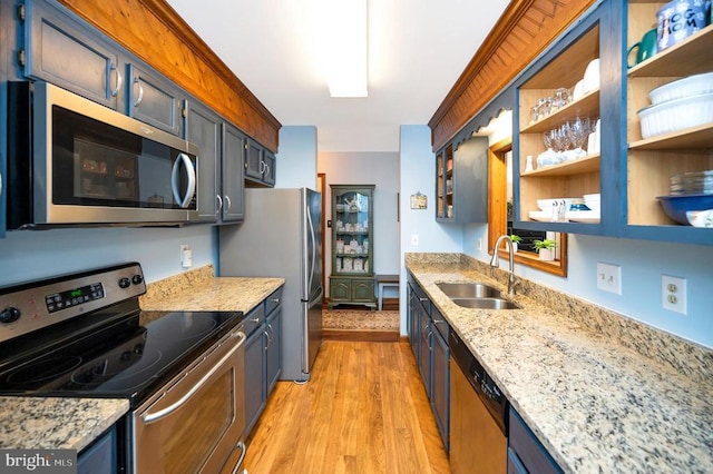 kitchen with stainless steel appliances, light wood-type flooring, light stone countertops, and sink