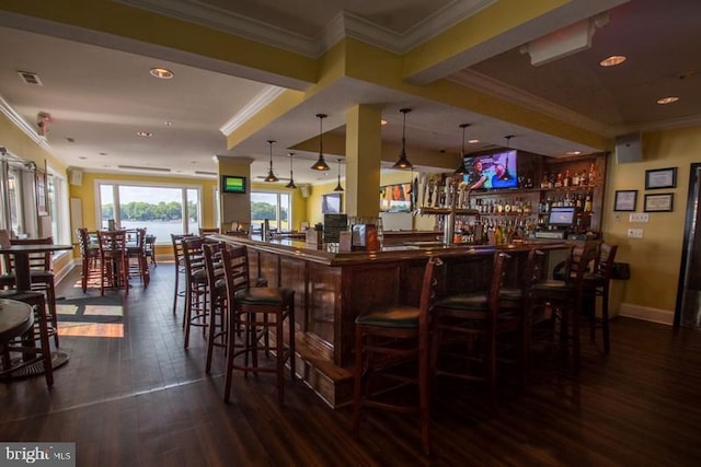 bar featuring dark hardwood / wood-style flooring, pendant lighting, and crown molding