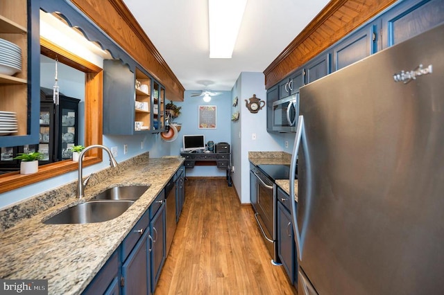 kitchen with sink, blue cabinets, ceiling fan, light wood-type flooring, and appliances with stainless steel finishes