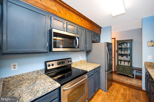 kitchen featuring light stone countertops, appliances with stainless steel finishes, light hardwood / wood-style flooring, and blue cabinetry