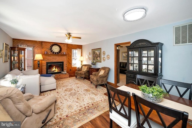 living room featuring ceiling fan, a fireplace, and wood-type flooring