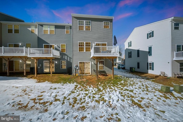 snow covered back of property featuring central AC unit