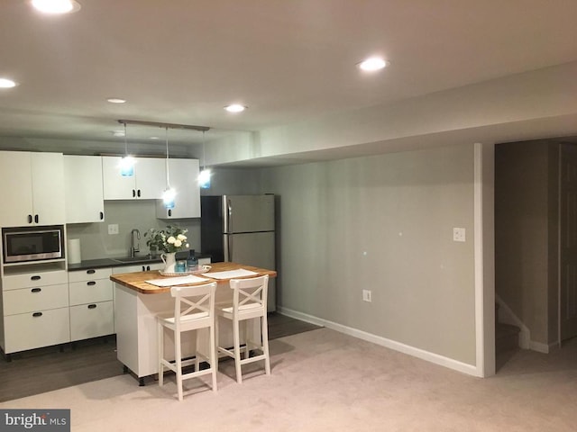 kitchen with white cabinetry, stainless steel appliances, a kitchen breakfast bar, hanging light fixtures, and a center island