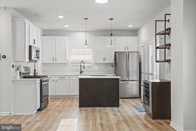 kitchen with stainless steel appliances, pendant lighting, white cabinets, and light hardwood / wood-style flooring