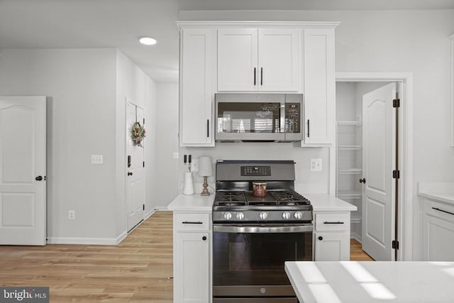 kitchen featuring appliances with stainless steel finishes, light wood-type flooring, and white cabinets