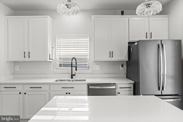 kitchen with sink, an inviting chandelier, hanging light fixtures, stainless steel appliances, and white cabinets