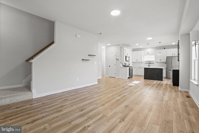 unfurnished living room with sink and light hardwood / wood-style floors