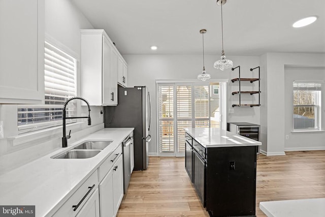 kitchen with dishwasher, sink, a kitchen island, and white cabinets