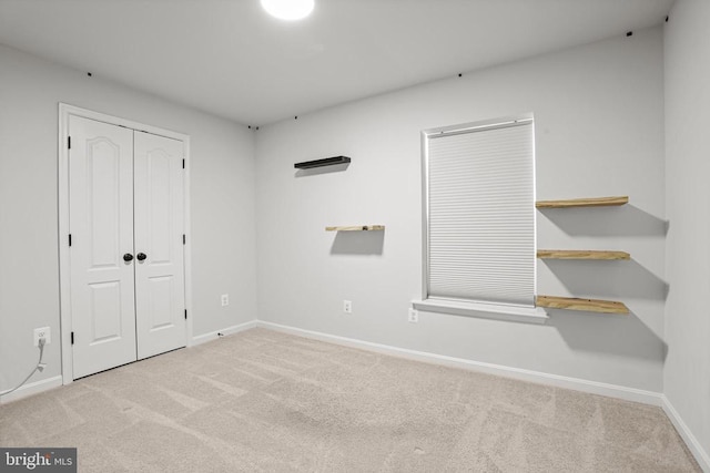 unfurnished bedroom with light colored carpet and a closet