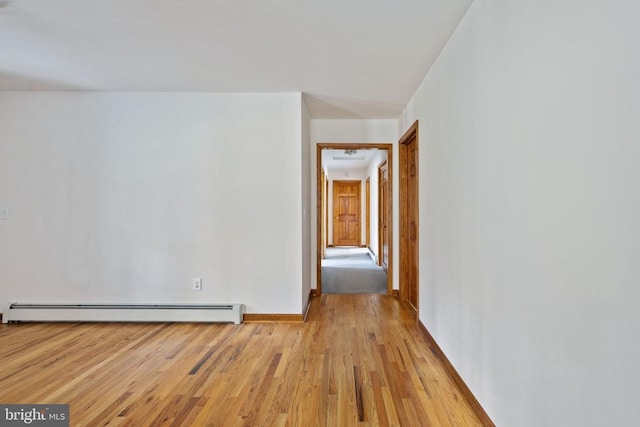 unfurnished room featuring baseboard heating and light hardwood / wood-style flooring