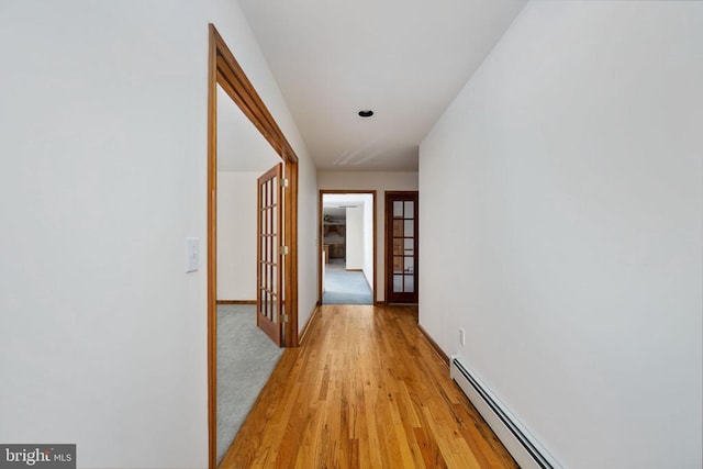 corridor with light hardwood / wood-style floors and a baseboard radiator