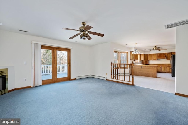 unfurnished living room featuring light colored carpet, ceiling fan with notable chandelier, and a baseboard radiator