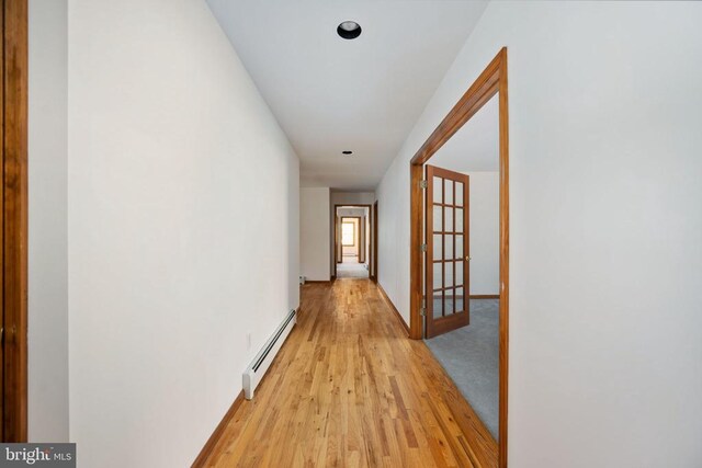 corridor featuring baseboard heating and light hardwood / wood-style flooring