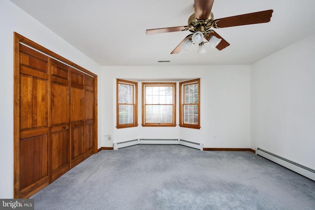 unfurnished bedroom with ceiling fan, a baseboard heating unit, a closet, and carpet floors