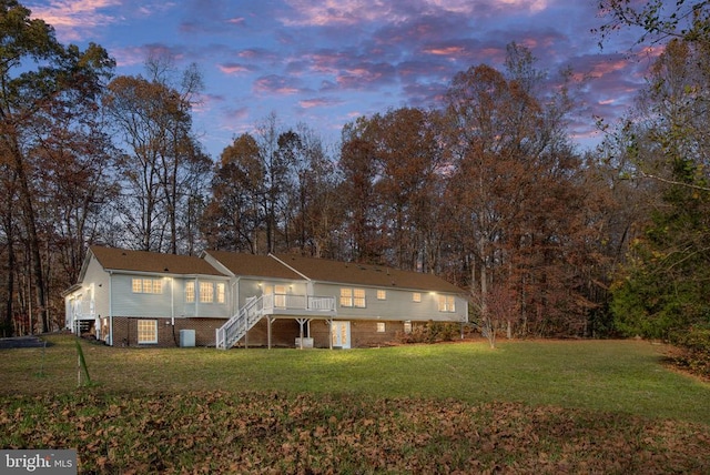 back house at dusk with a deck and a yard