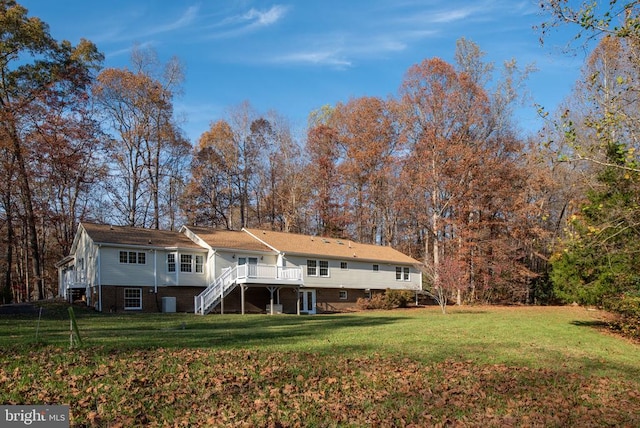 rear view of house featuring a wooden deck and a yard