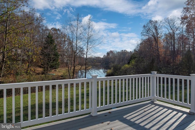 wooden deck with a water view and a lawn