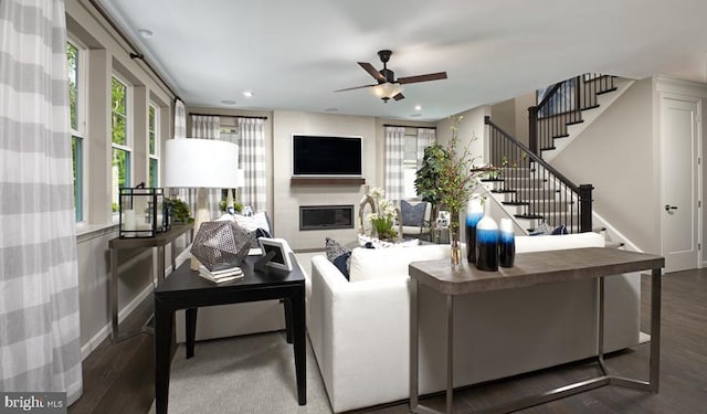 living room featuring dark wood-type flooring, ceiling fan, and a fireplace