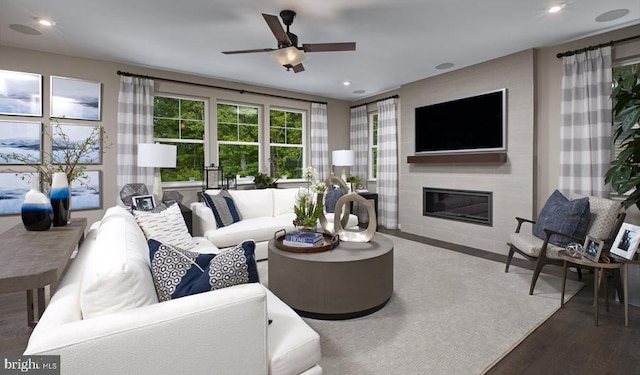 living room with dark wood-type flooring, a tile fireplace, and ceiling fan