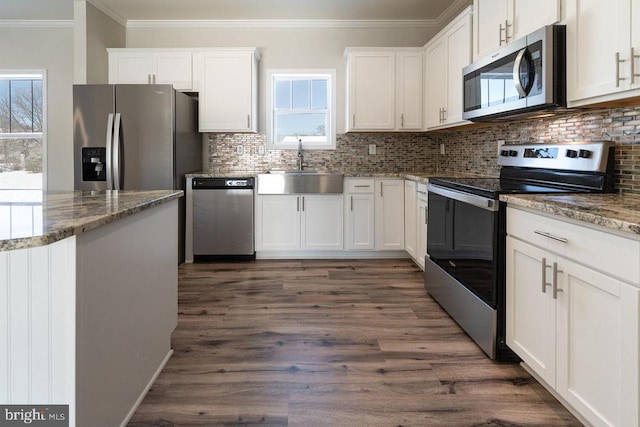 kitchen with appliances with stainless steel finishes, dark hardwood / wood-style floors, light stone countertops, white cabinets, and sink