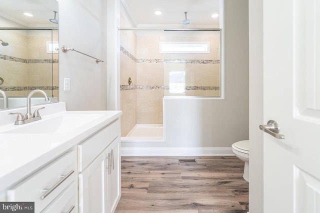 bathroom with toilet, a tile shower, hardwood / wood-style flooring, crown molding, and vanity