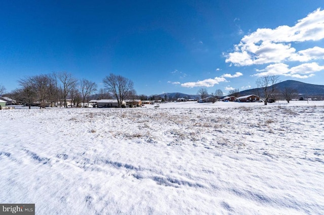 yard covered in snow featuring a mountain view