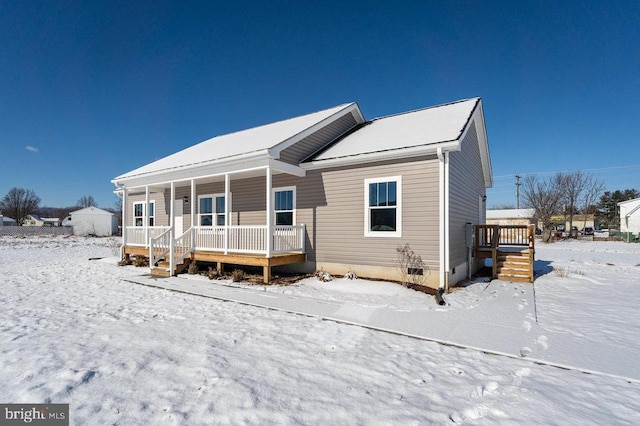 snow covered house featuring covered porch