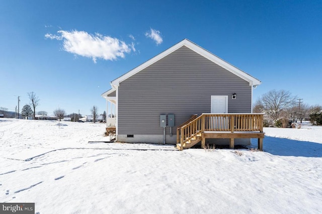 snow covered back of property featuring a deck