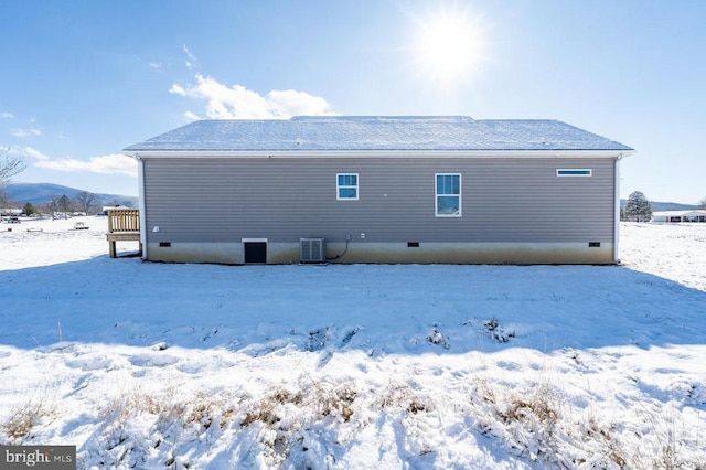 snow covered house featuring central AC unit and a mountain view