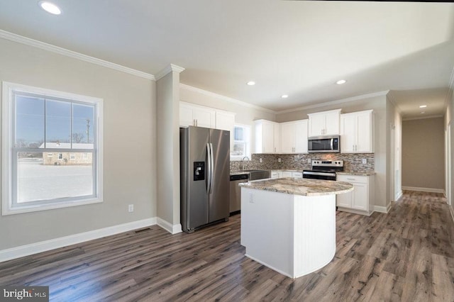 kitchen featuring backsplash, a kitchen island, white cabinetry, appliances with stainless steel finishes, and light stone counters