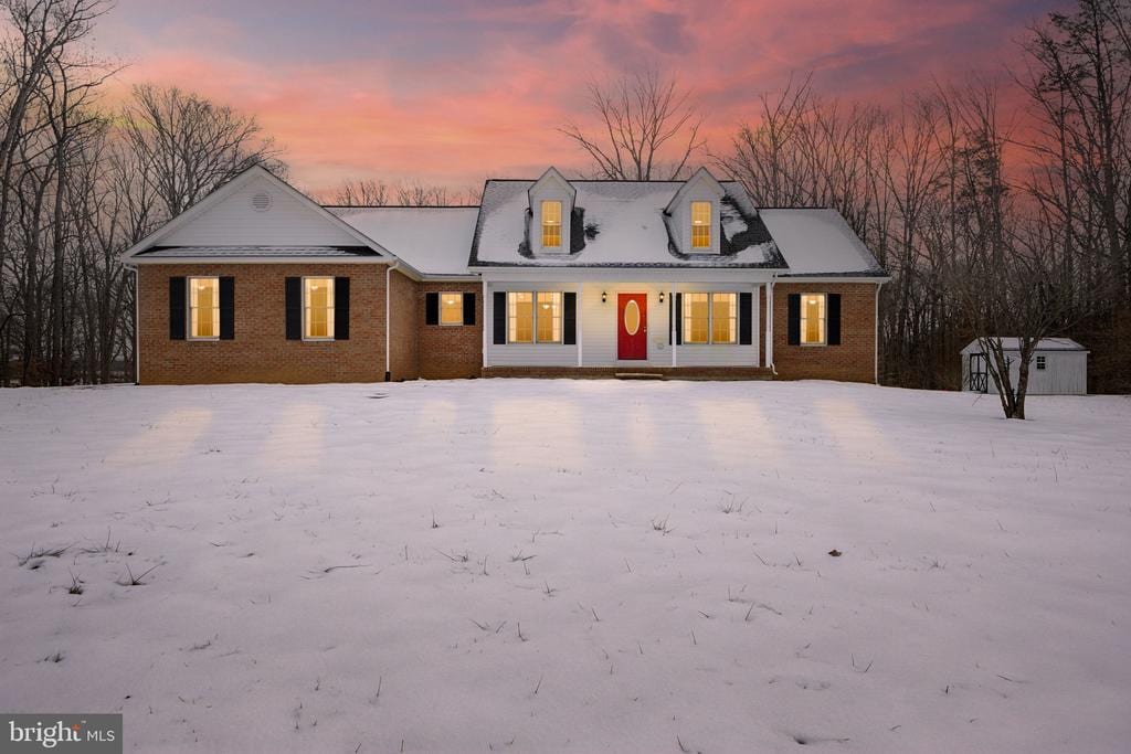 cape cod-style house with a storage shed