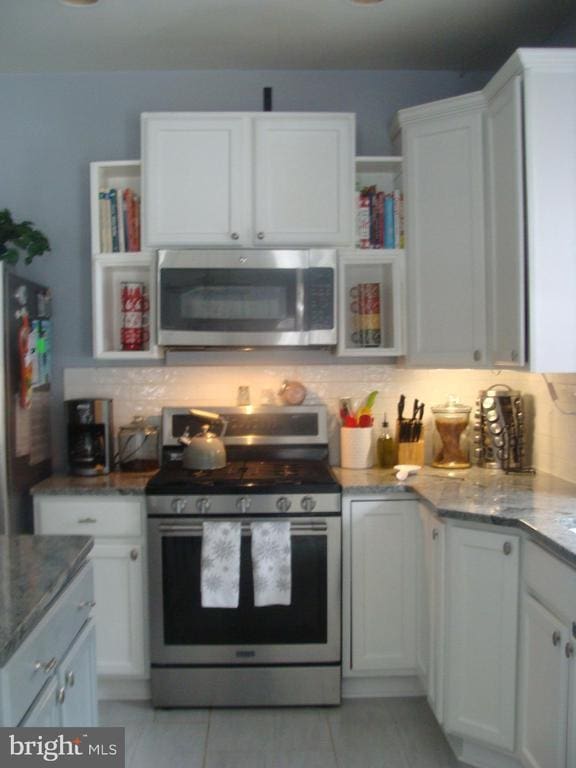 kitchen with light stone counters, white cabinets, and appliances with stainless steel finishes