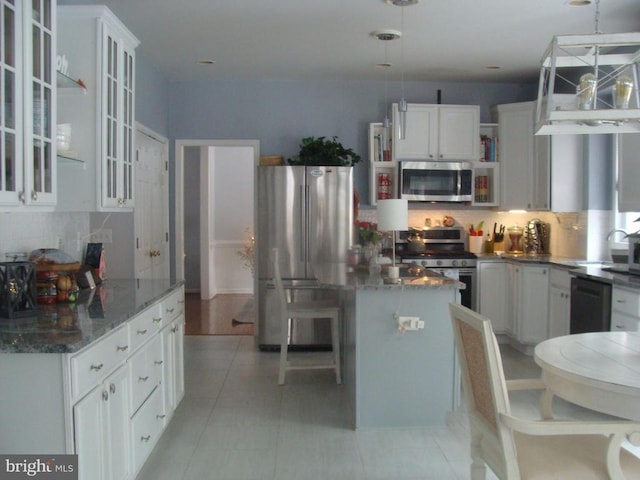 kitchen featuring stainless steel appliances, white cabinetry, hanging light fixtures, and backsplash