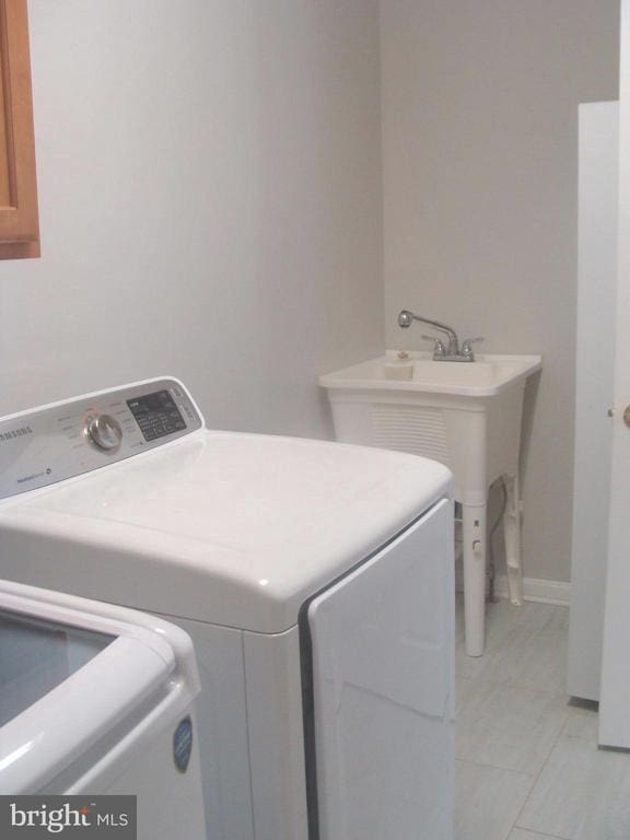 clothes washing area featuring light tile patterned flooring and washer and clothes dryer