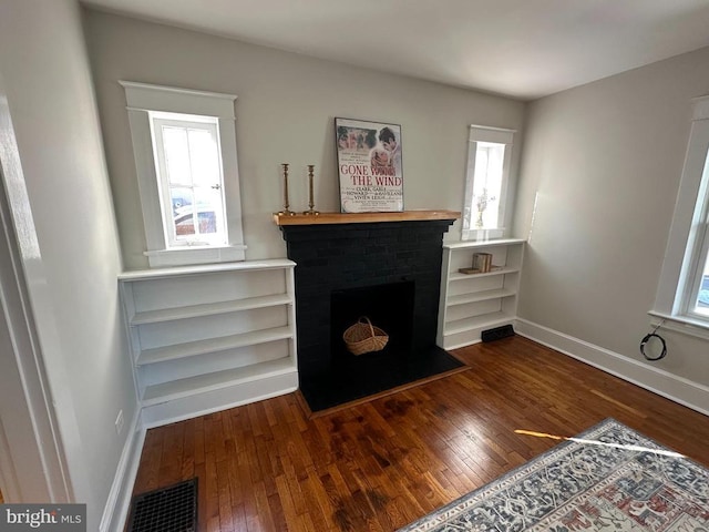 living room featuring dark hardwood / wood-style flooring and a brick fireplace