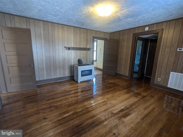 unfurnished living room with a textured ceiling, dark hardwood / wood-style flooring, and wooden walls