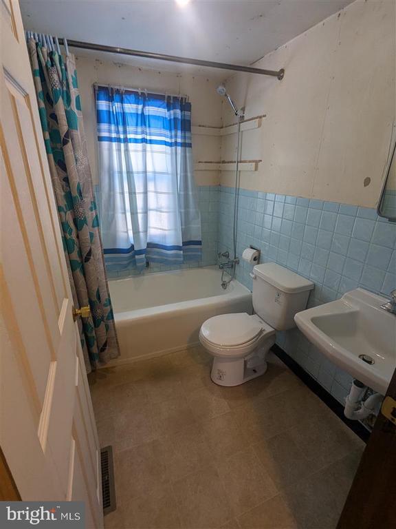 full bathroom featuring sink, tile walls, toilet, and shower / bath combo