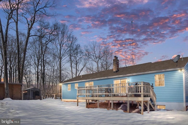 snow covered back of property with a deck