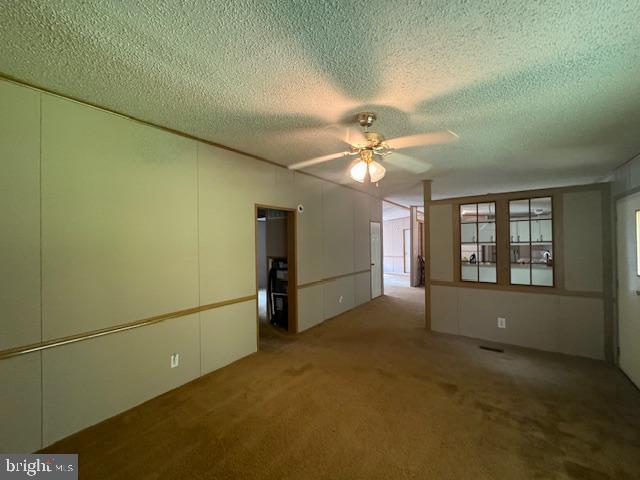 carpeted empty room with ceiling fan and a textured ceiling